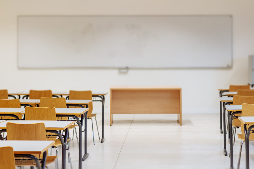 Empty classroom with desks, whiteboard, and teacher podium