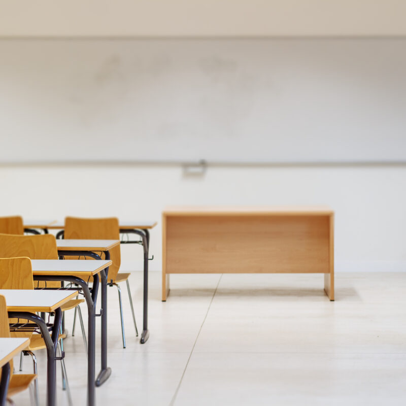 Empty classroom with desks, whiteboard, and teacher podium
