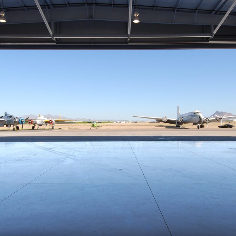 Interior view of aircraft hangar with vintage planes outside