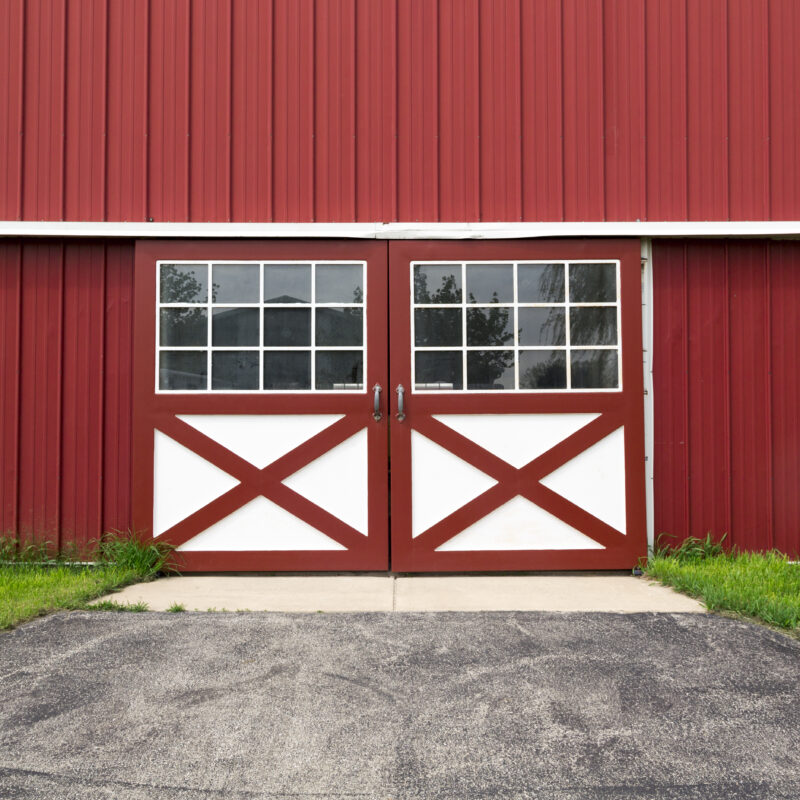 Red steel horse barn with double Dutch doors