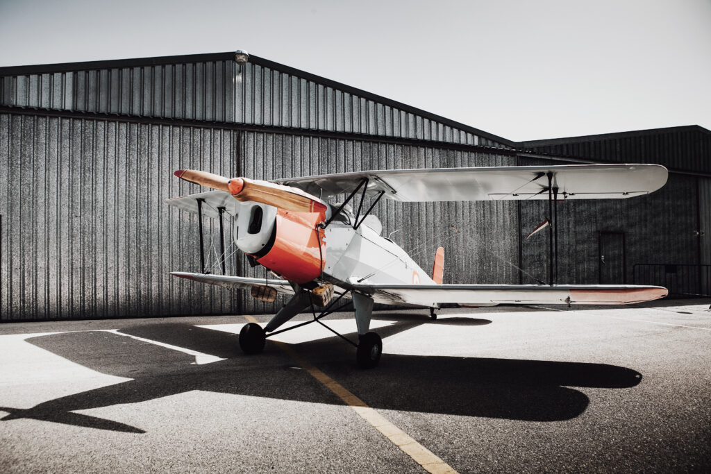 Aircraft parked beside a steel aircraft hangar