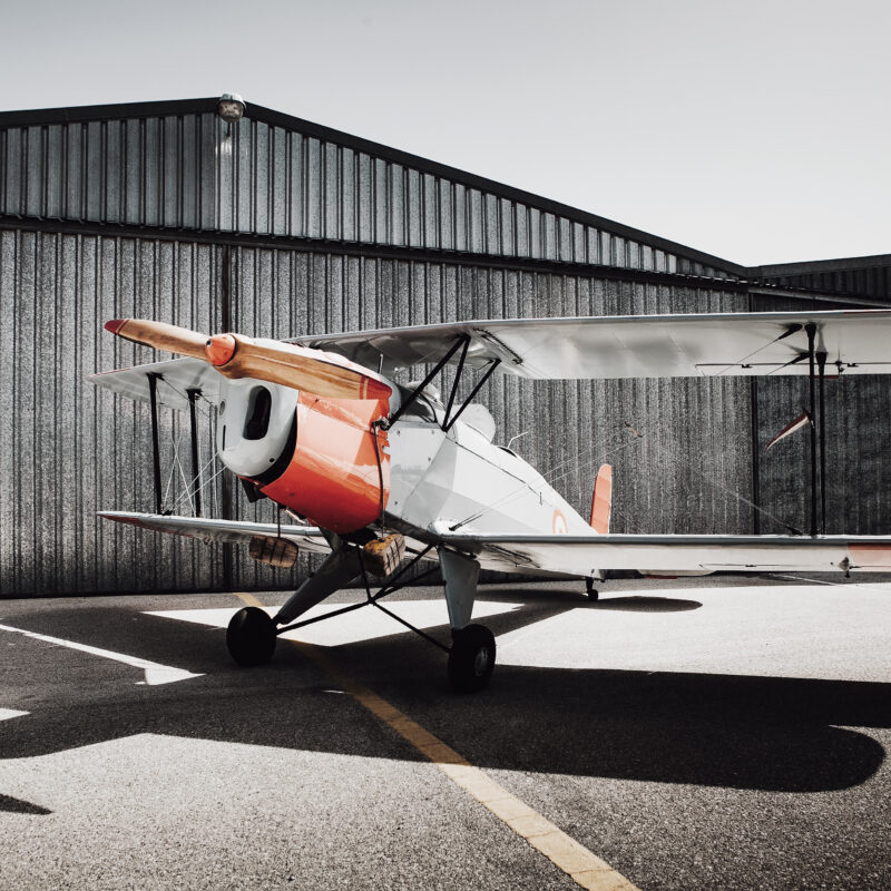 Aircraft parked beside a steel aircraft hangar