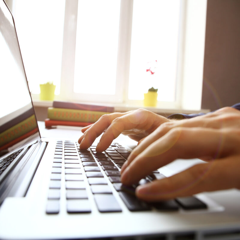 Hands typing on laptop keyboard in office