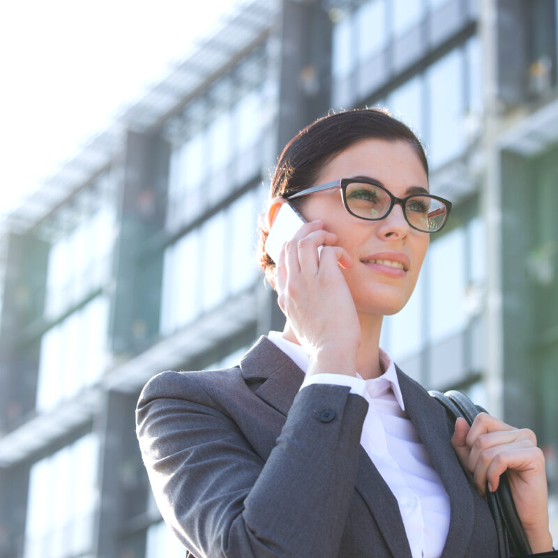 Businesswoman talking on phone outside modern steel building