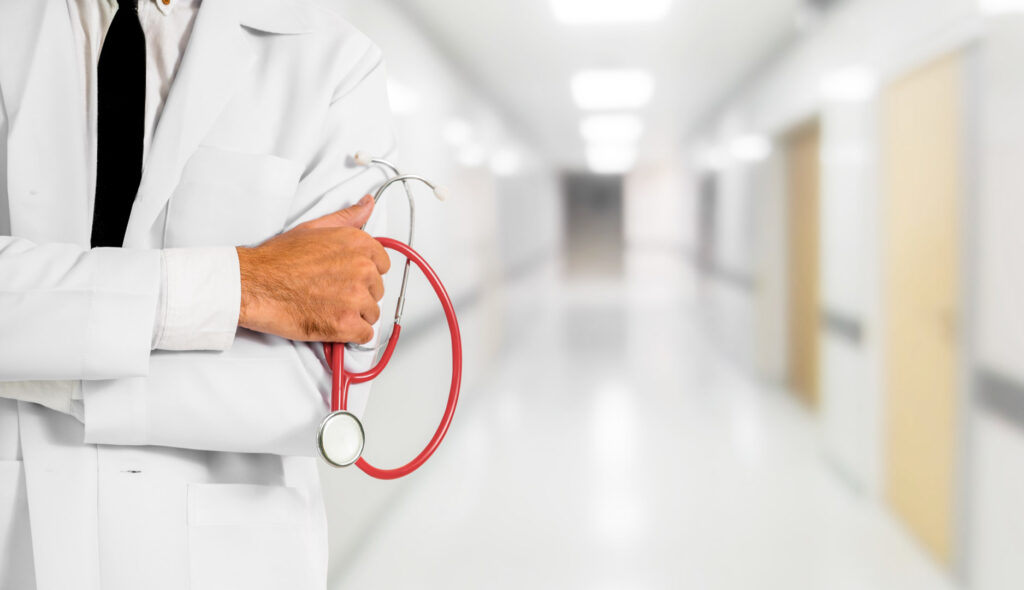 Doctor holding red stethoscope in hospital hallway