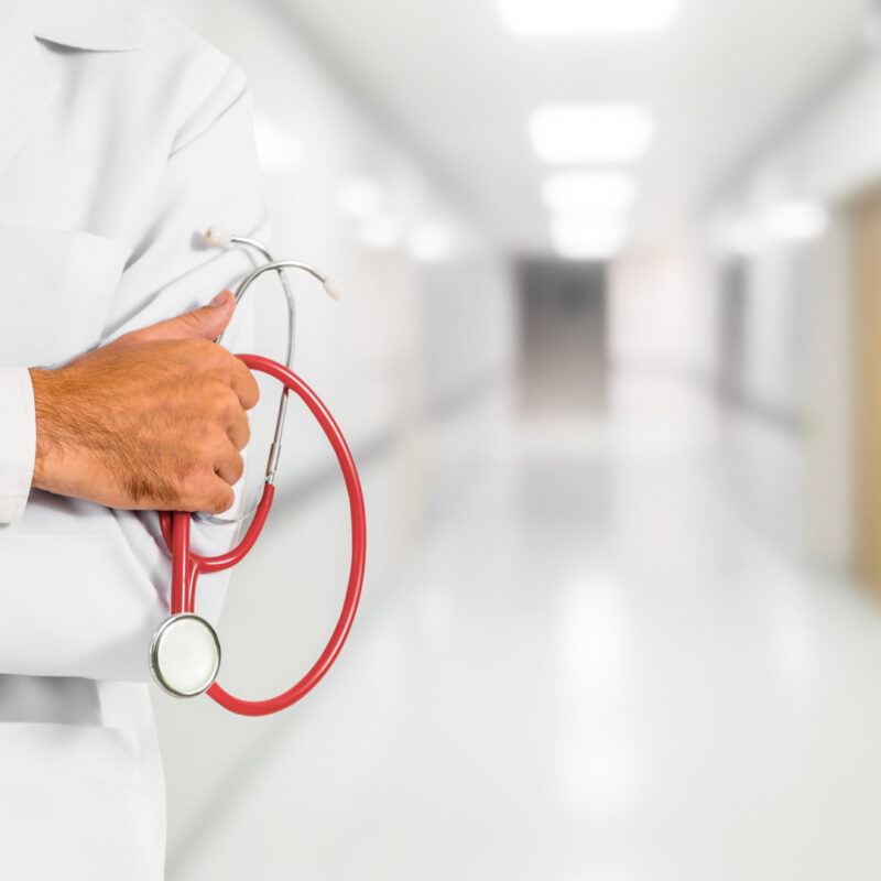 Doctor holding red stethoscope in hospital hallway
