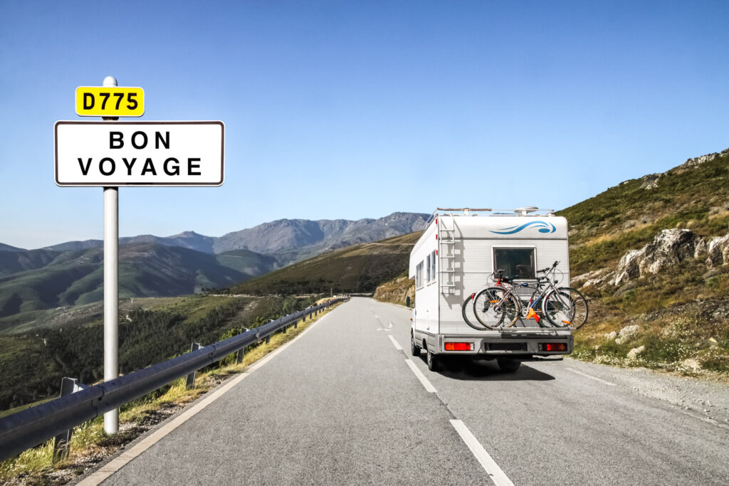 Motorhome with bicycles on mountain road near Bon Voyage sign