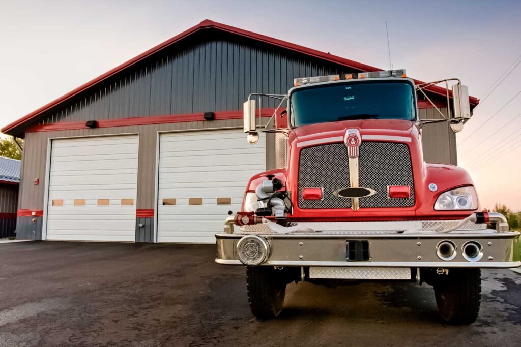 Red fire truck parked in front of a steel building garage