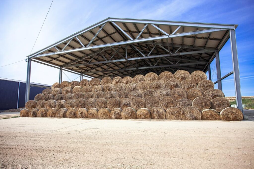 Steel agricultural building storing hay bales under covered roof