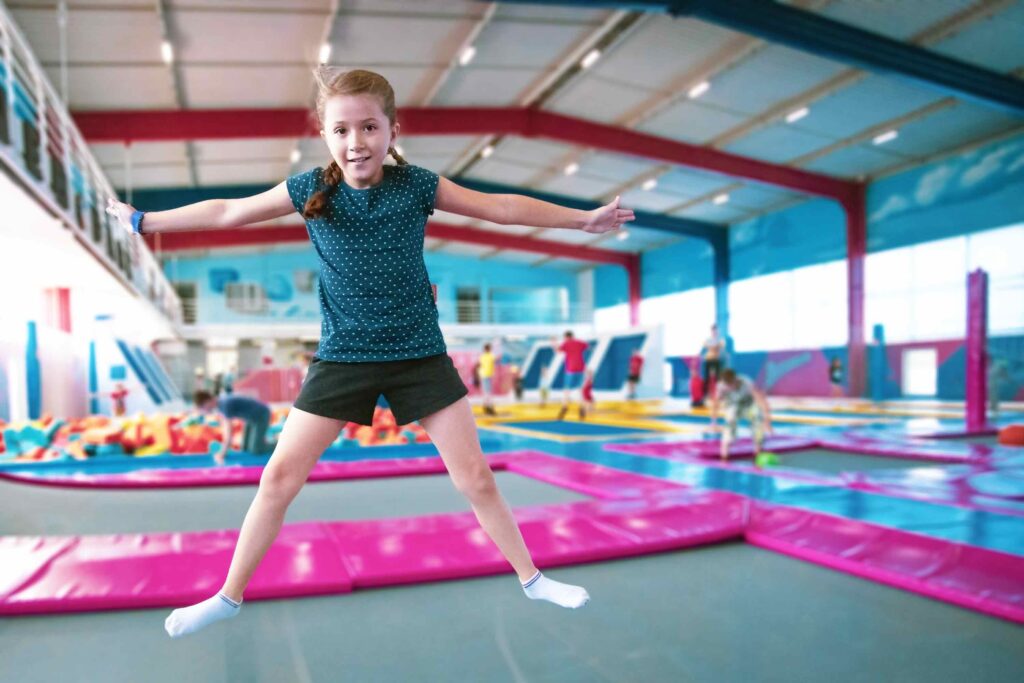 Girl jumping in indoor gymnastics training facility with steel building structure