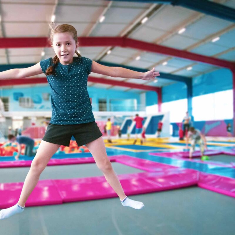 Girl jumping in indoor gymnastics training facility with steel building structure