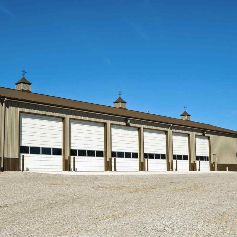 Metal building with multiple garage doors and gravel lot
