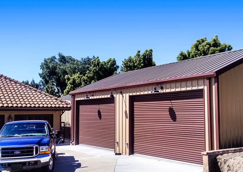 Metal garage building with two roll-up doors and truck parked outside