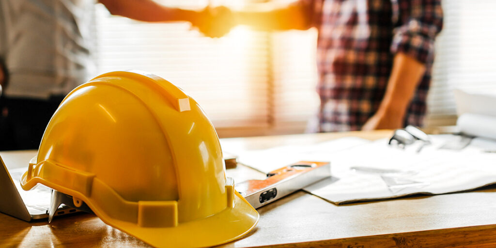 Yellow hard hat on construction plans for metal building project
