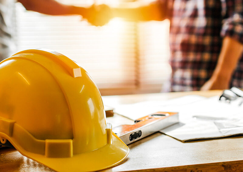 Yellow hard hat on construction plans for metal building project