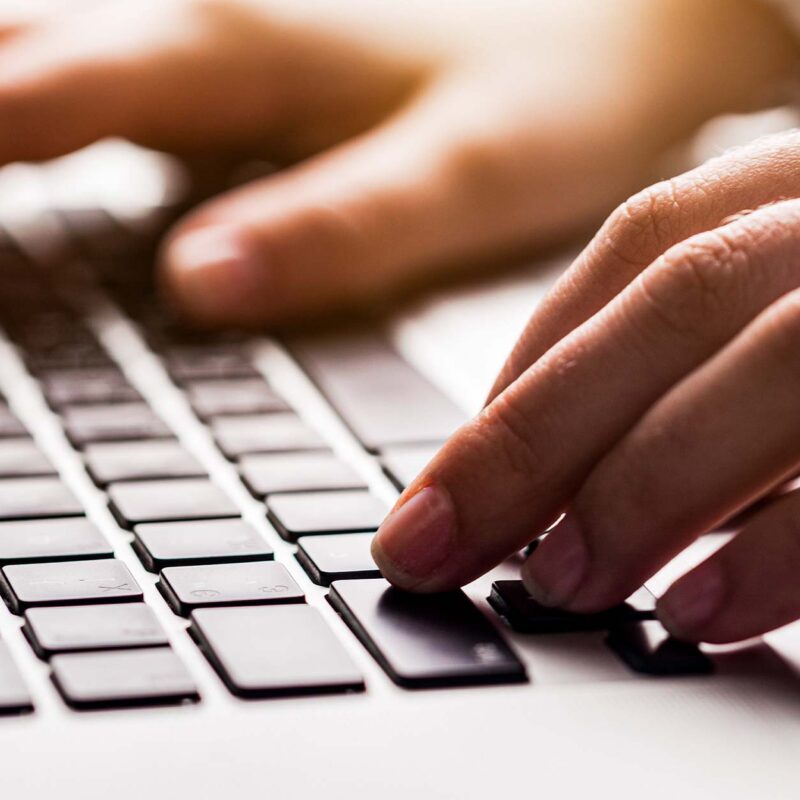 Hands typing on laptop keyboard in close-up computer work scene
