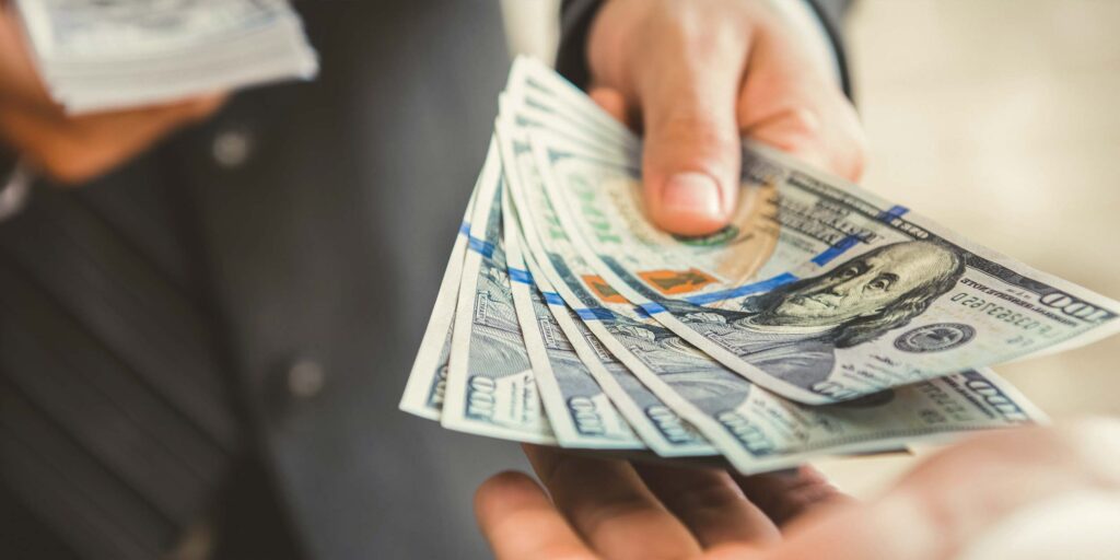 Hand exchanging cash with hundred-dollar bills