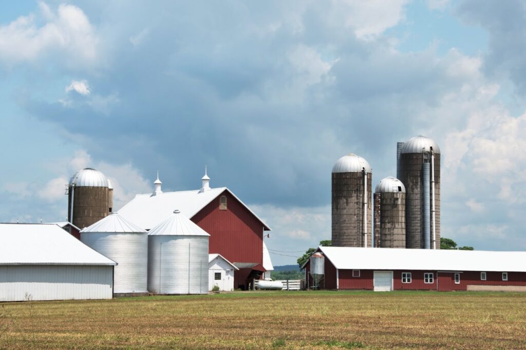 Red barn and white metal agricultural buildings with silos