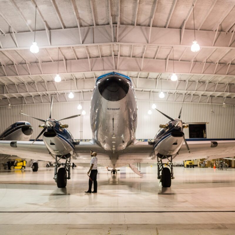 Aircraft in a steel aircraft hangar with a person nearby
