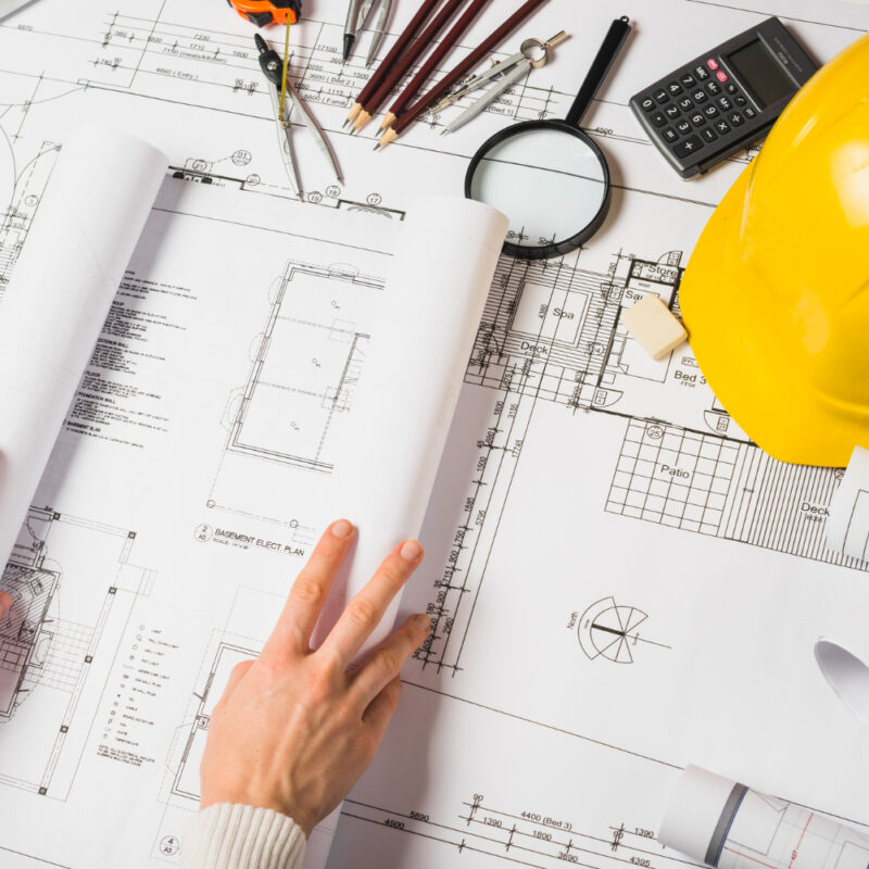 Architectural blueprints with hard hat and drafting tools