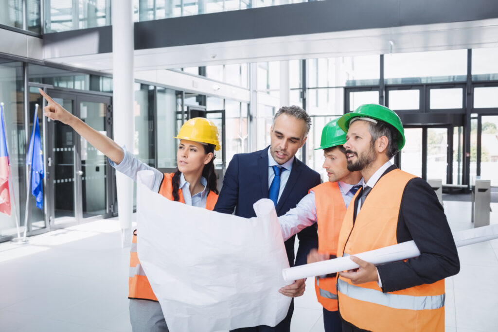 Construction team reviewing blueprints in a metal building lobby
