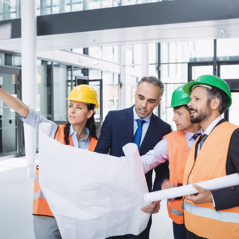 Construction team reviewing blueprints in a metal building lobby