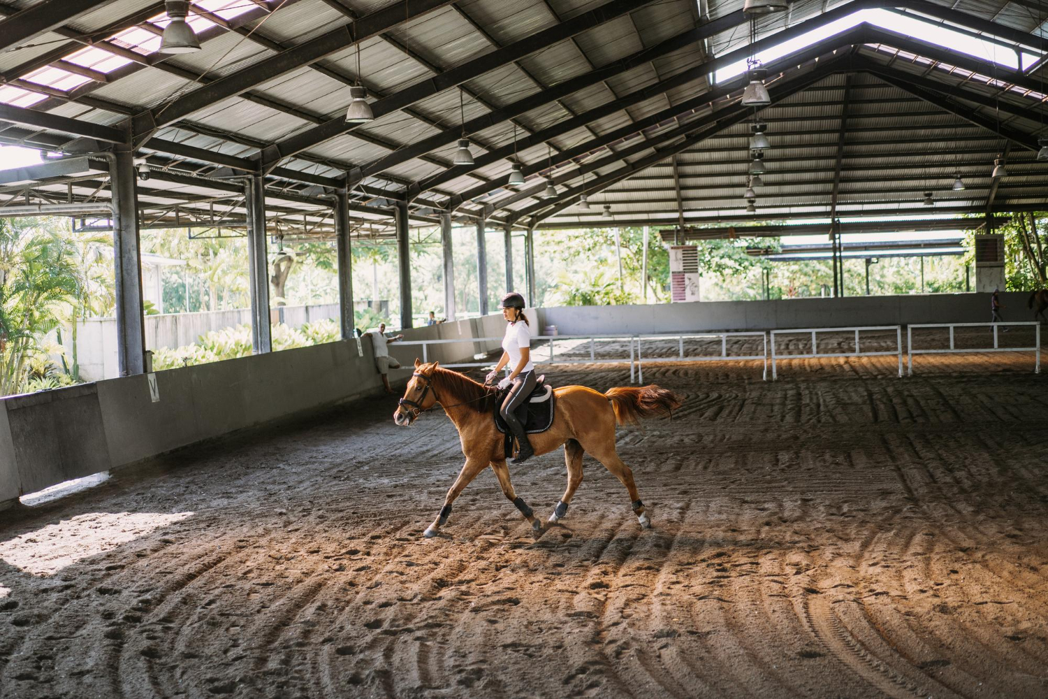 A girl riding on horse in indoor riding arena