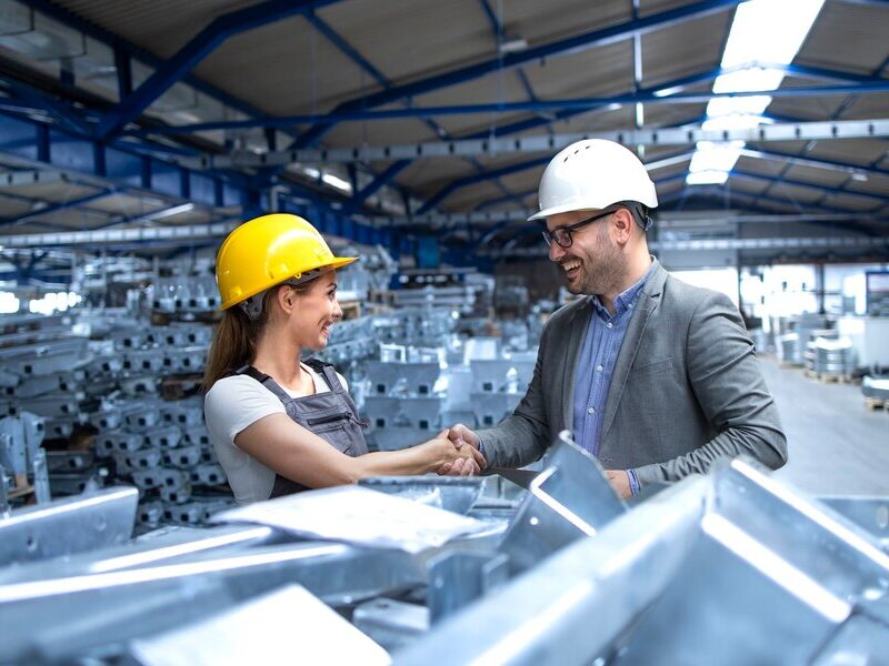 Two workers shaking hands inside a steel building