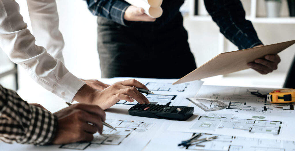 Team reviewing steel building blueprints with calculator and plans