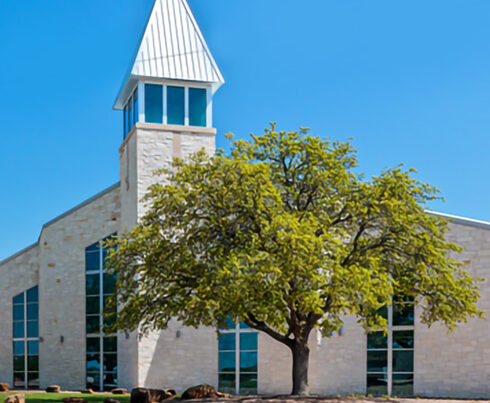 Stone church building with steeple and tree exterior