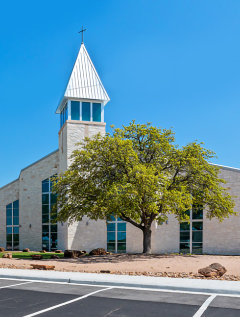 Stone church building with steeple and tree exterior