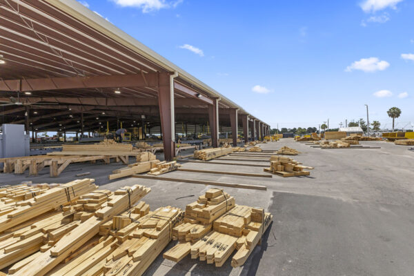 Steel commercial metal building under construction with lumber stacks