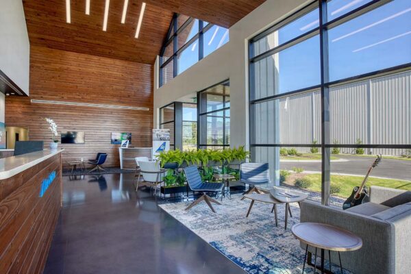 Modern commercial metal building lobby with glass walls and wood ceiling