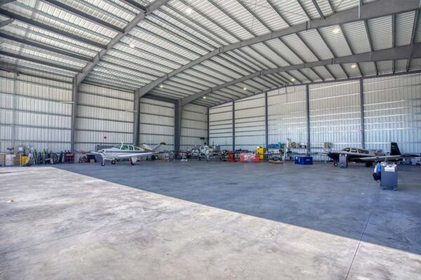 Aircraft hangar with small planes inside, steel building interior