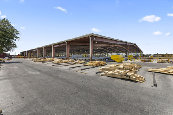 Steel industrial building under construction with lumber stacks