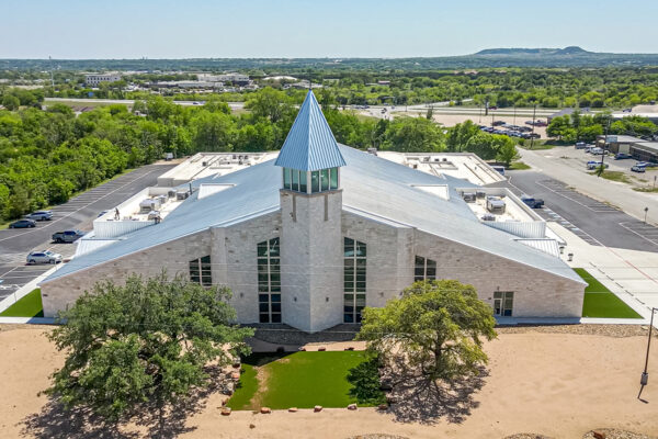 Metal church building with blue steeple and parking lot