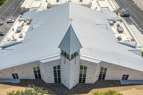 Aerial view of a large commercial metal building with white roof