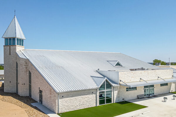 Steel church building with tall steeple and metal roof