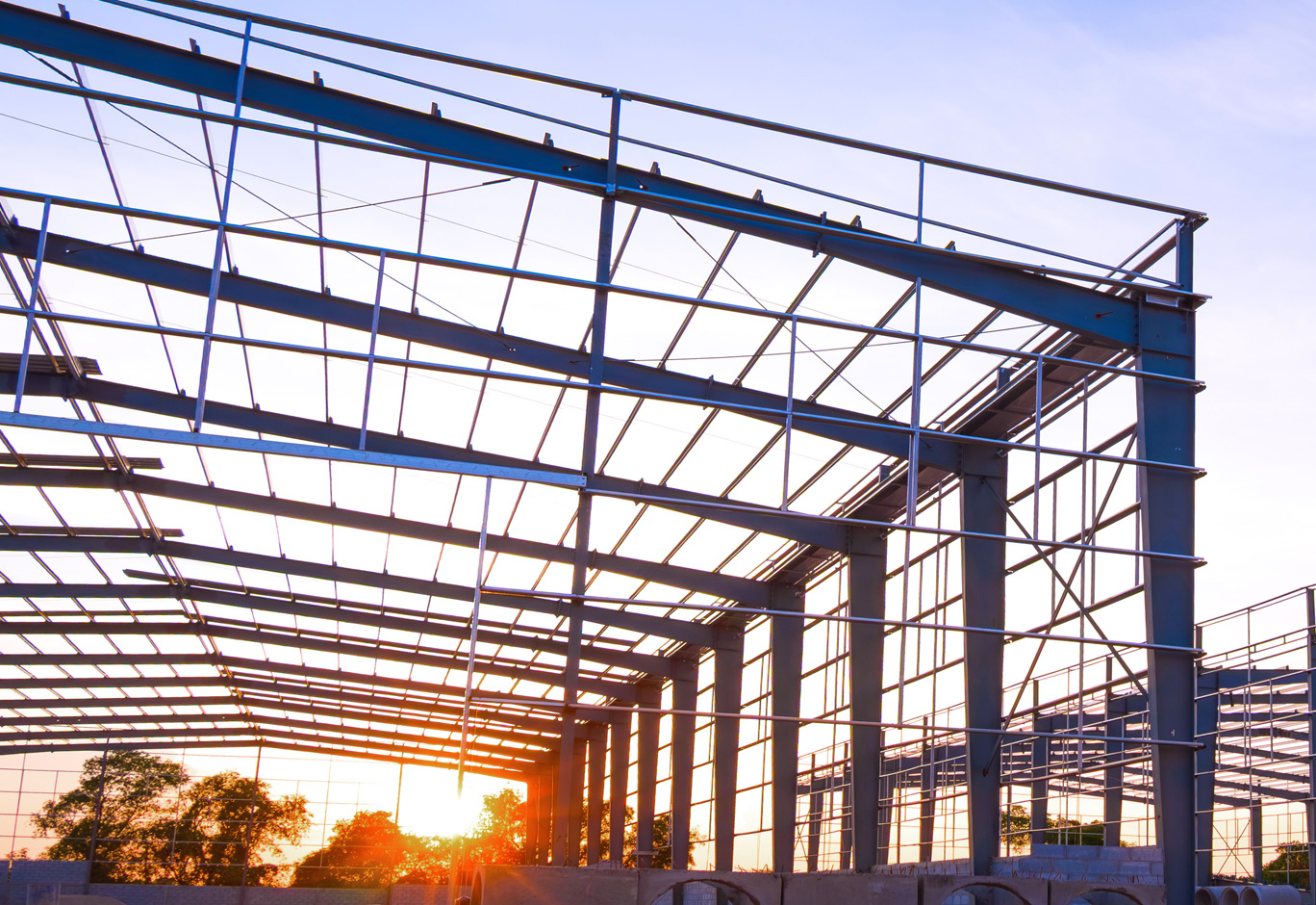 Steel building frame under construction at sunset