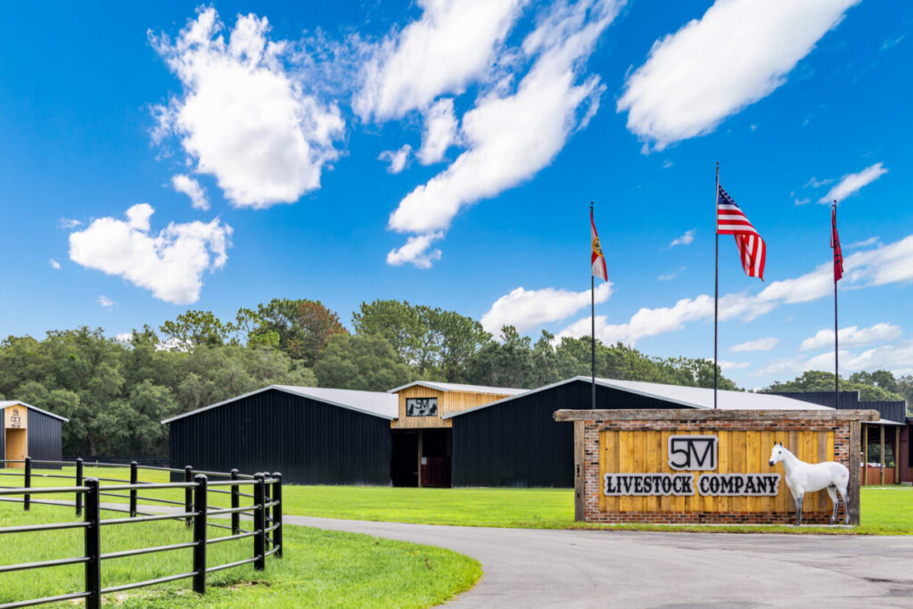 Steel horse barn with livestock company sign and paddock