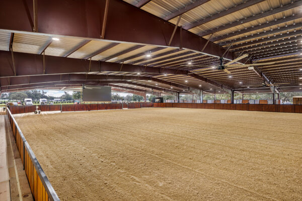 Metal building structural framework supporting a steel riding arena