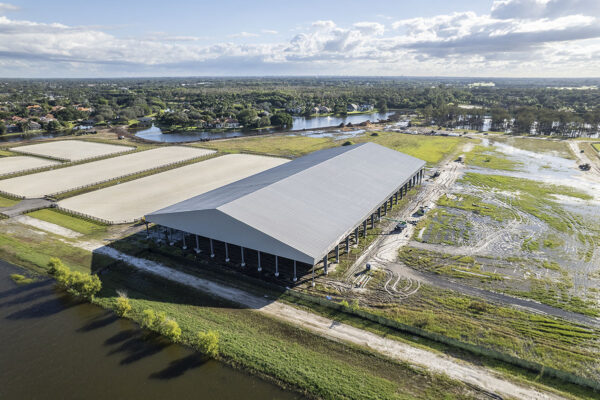 Covered riding arena with steel roof and adjacent horse arenas