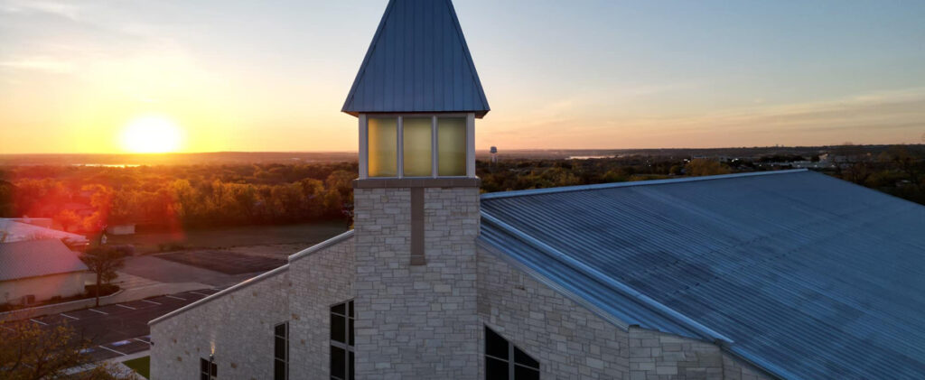 Stone church with metal roof at sunset