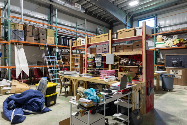 Interior of a metal building workshop with storage shelves and worktables