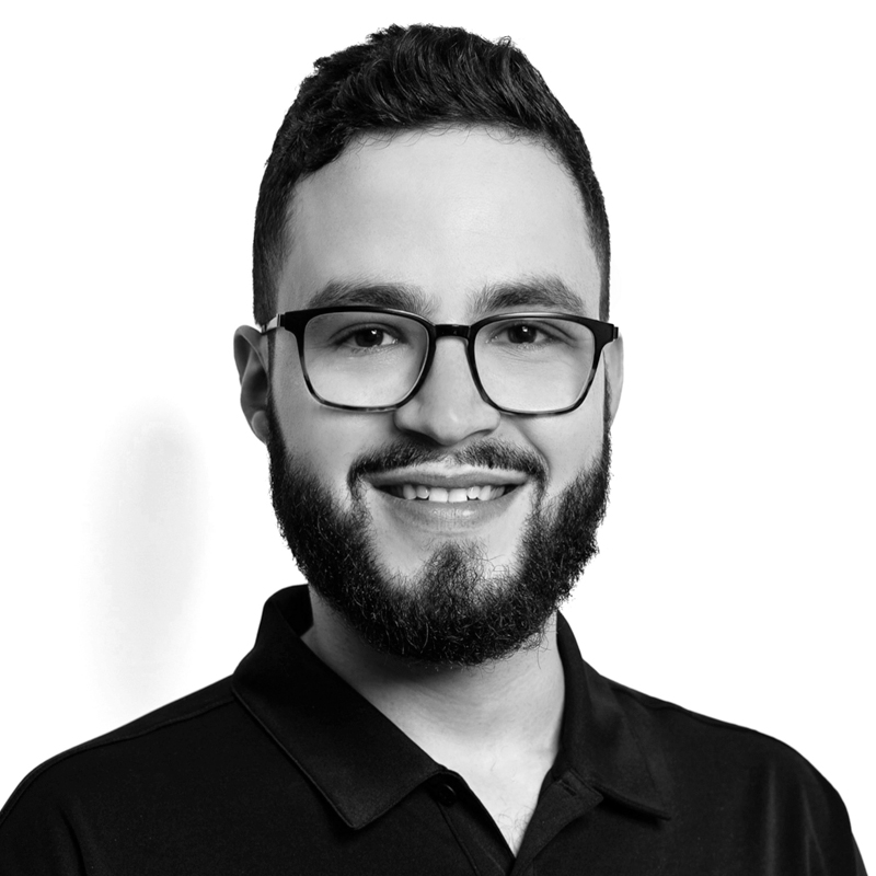 Smiling bearded man with glasses in black polo shirt