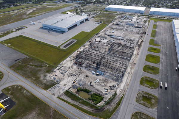 Aerial view of steel building construction site beside airport runway