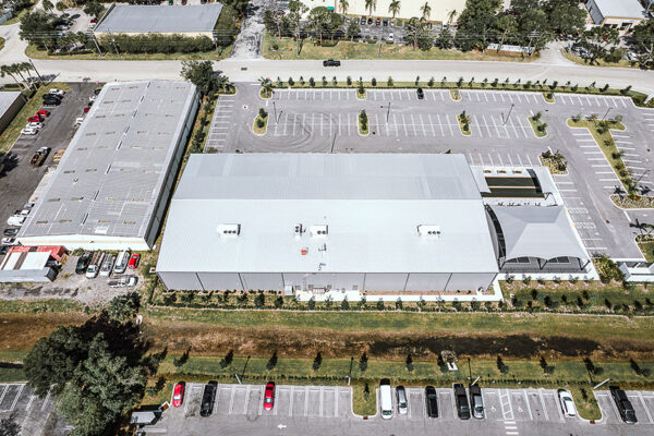 Aerial view of large steel building with parking lot
