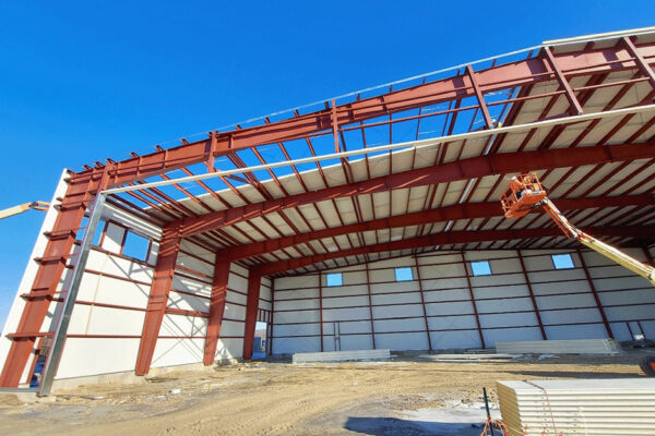 Steel building construction with red structural frame and lift bucket