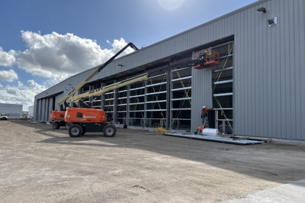 Steel building under construction with boom lifts and workers