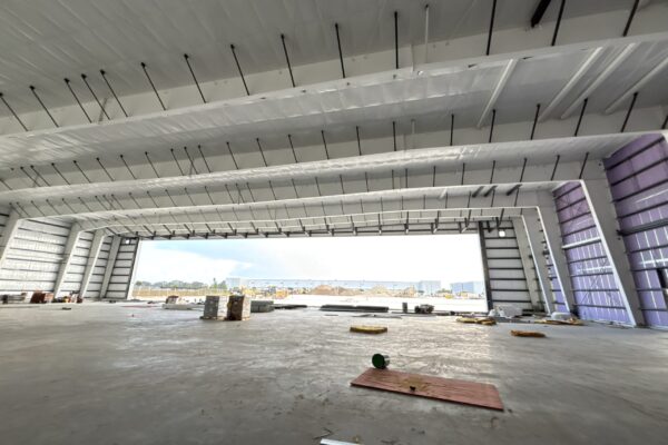 Interior of large steel building under construction with open bay doors